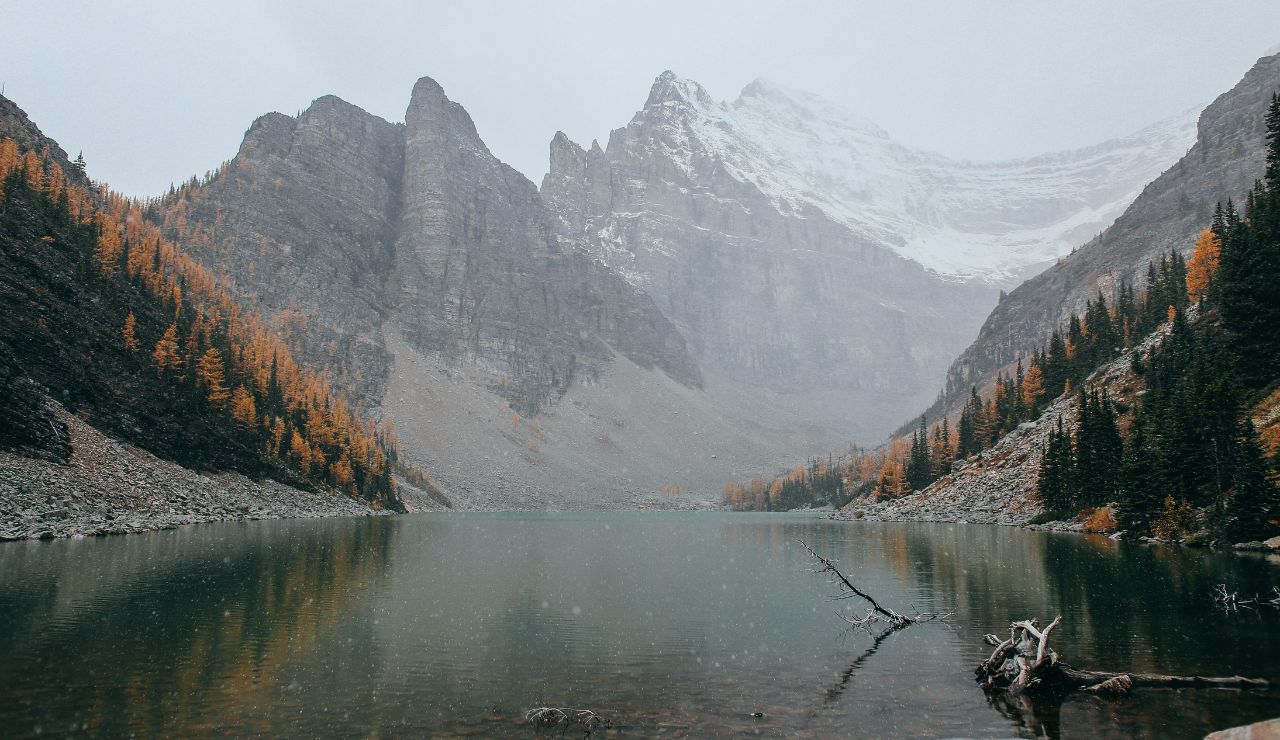 Clear mountain lake surrounded by cliffs and pine forest, with paddleboarder or cliff jumper mid-action.