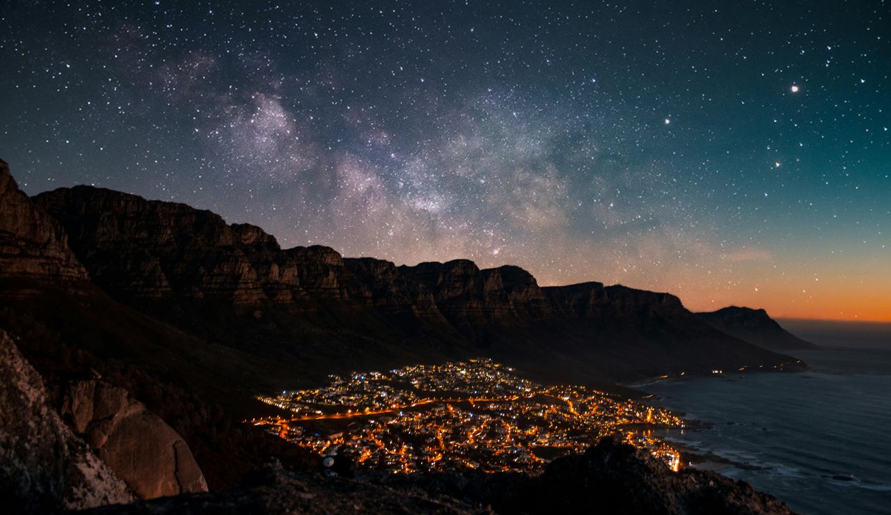 Starry sky with silhouetted mountains or tents, preferably with Milky Way visible; long-exposure night shot.