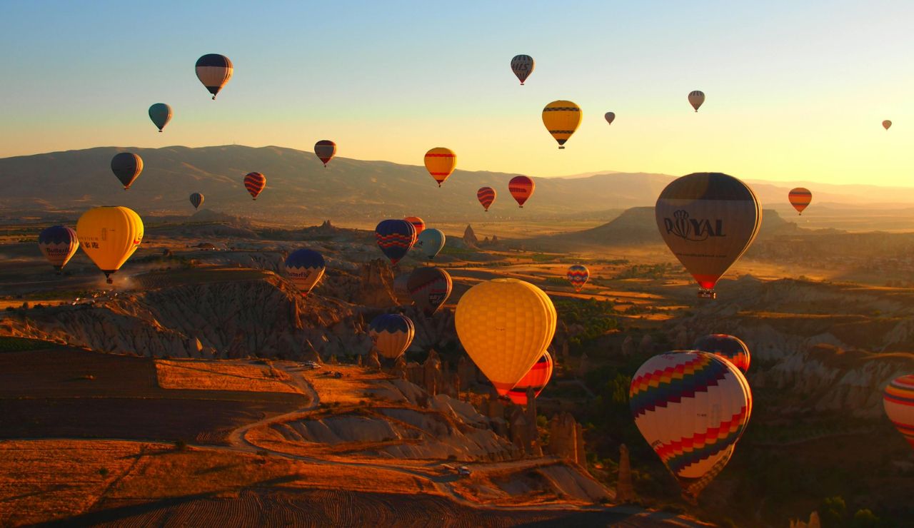 Hot air balloon flying over rolling vineyards at sunrise