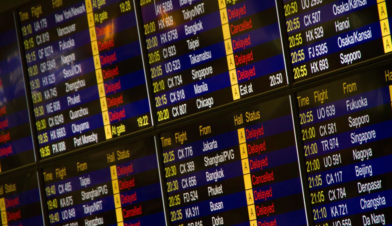A digital departures board showing canceled flights with headlines about airline strikes.