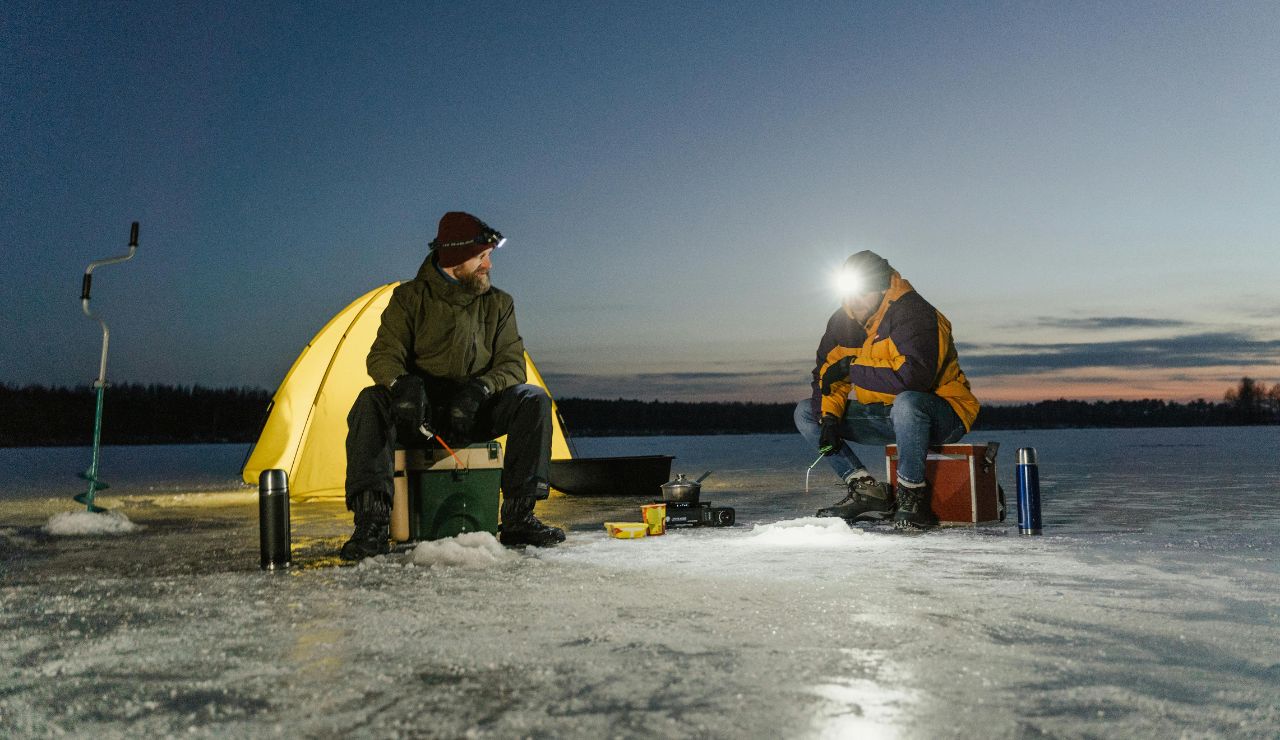 Small tent pitched beside a Nordic lake at sunset, with vast wilderness and pine trees around