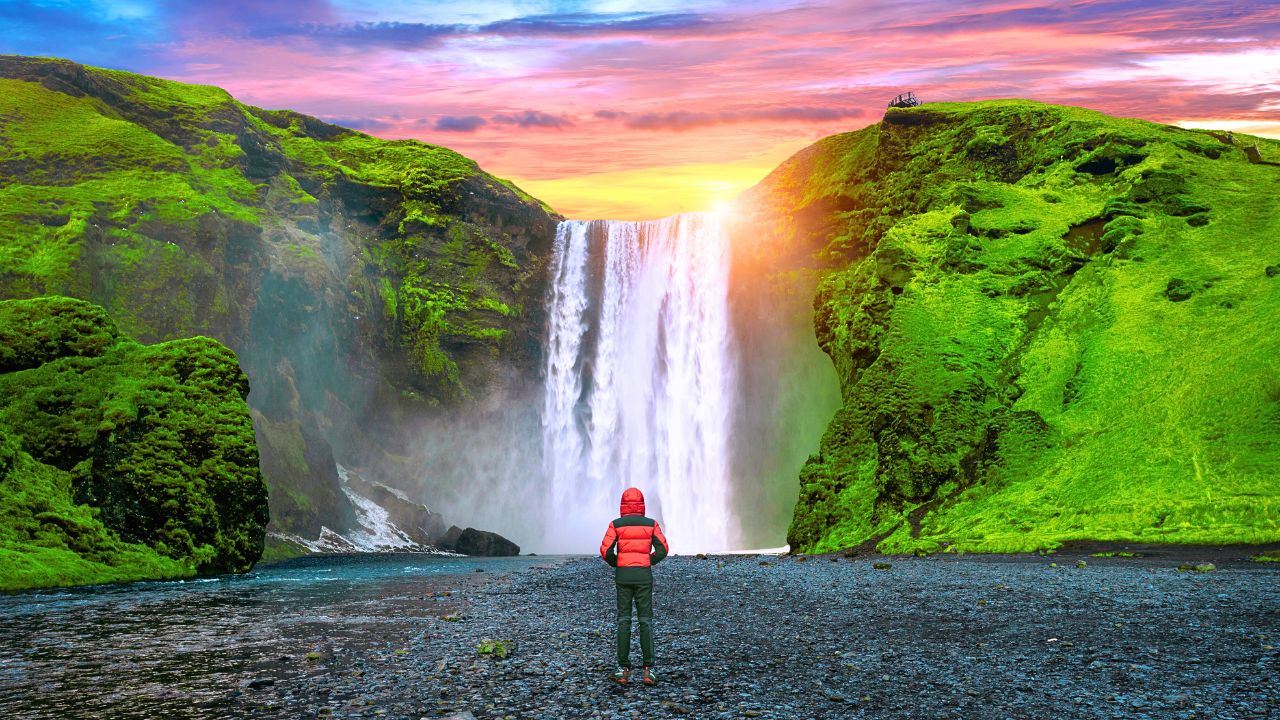 A sweeping view of a dramatic waterfall surrounded by forested cliffs and mist