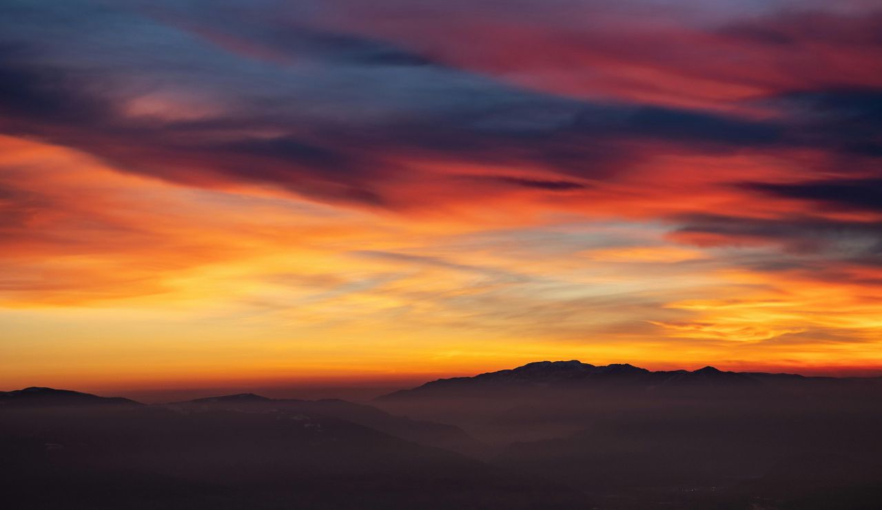 Sunset colors casting warm glow over colorful, rippling hills