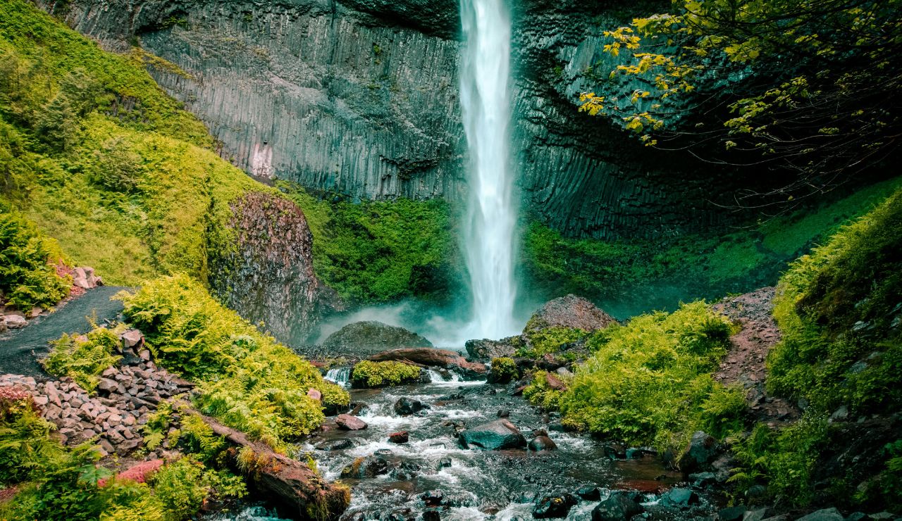 Tiered falls framed by vertical basalt columns and dense greenery