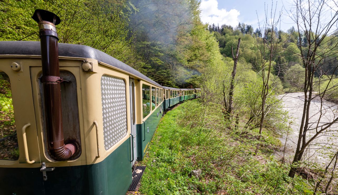 Train traveling along the St. Lawrence River with cliffs and quaint villages visible, bright and inviting.