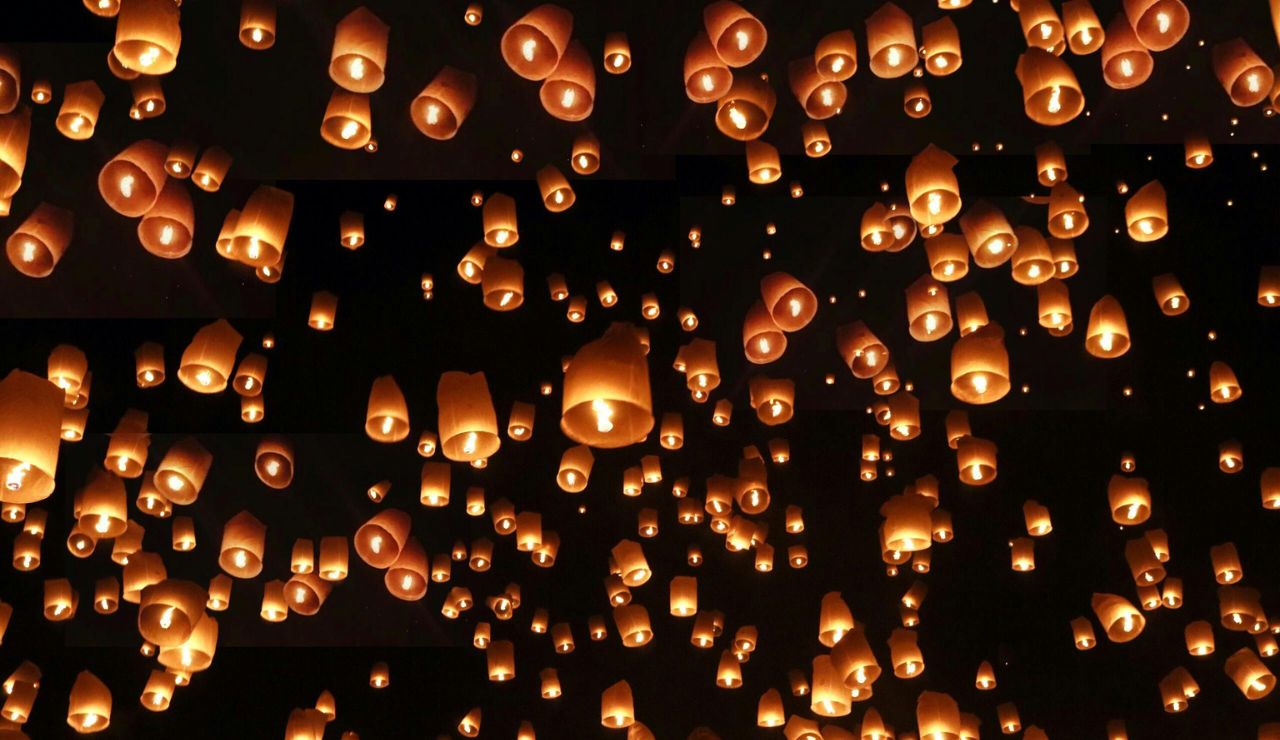Hundreds of lanterns rising into the night sky during Yi Peng in Thailand.
