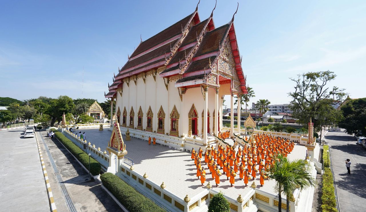monks walk by golden temples at sunrise in Luang Prabang.