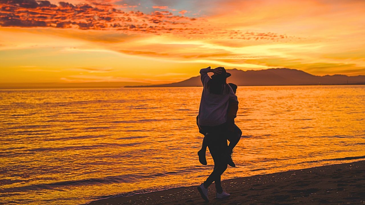Couple walking along the beach at sunset during a summer getaway