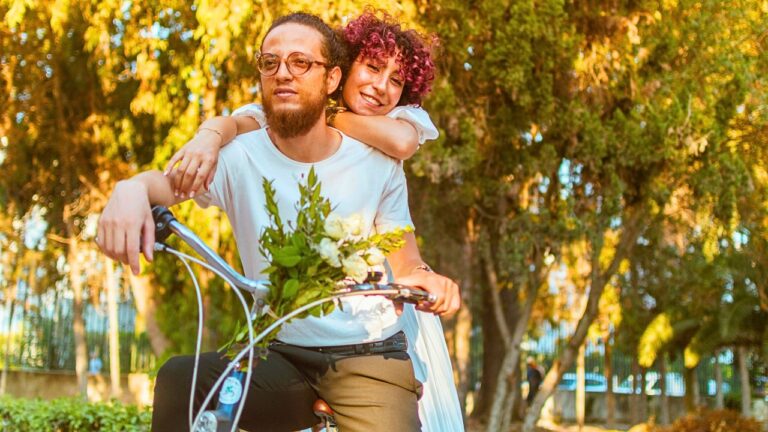 A couple cycling along a tree-lined Canadian rail trail in autumn
