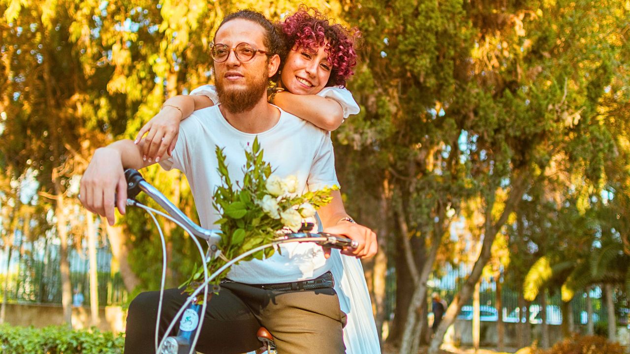A couple cycling along a tree-lined Canadian rail trail in autumn