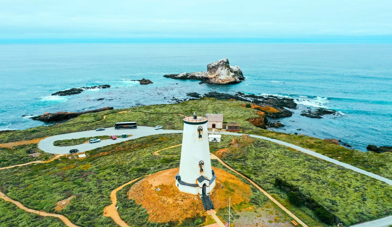 View of Cape Reinga lighthouse with cliffside trail and ocean meeting point in Northland.