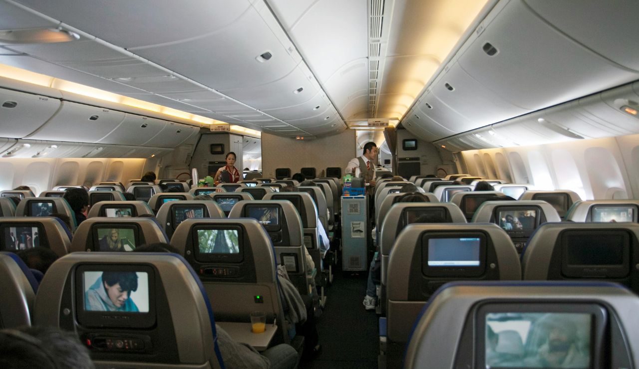Couple watching synced movies on personal screens during a long-haul flight.
