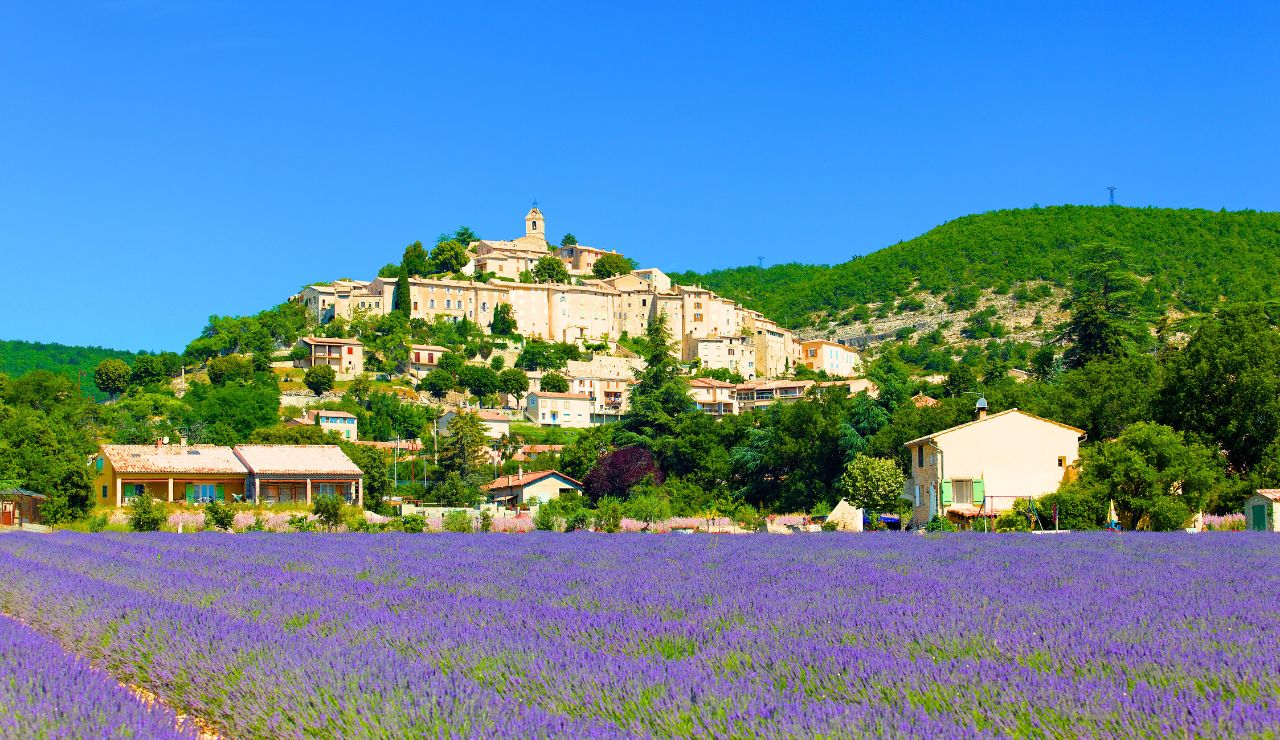 A hilltop village with pastel stone houses, waterfalls, and a chapel nestled in cliffs