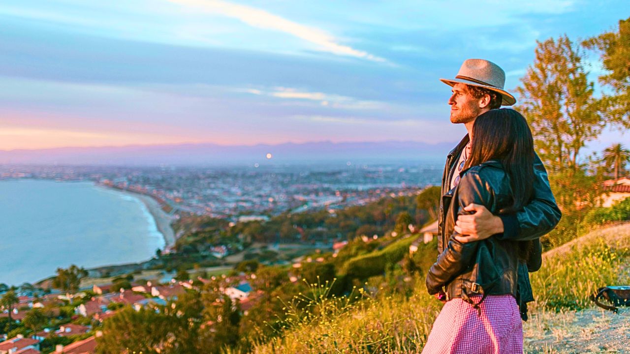 Couple embracing at a scenic lookout during sunset, capturing a romanticĀ travelĀ moment.