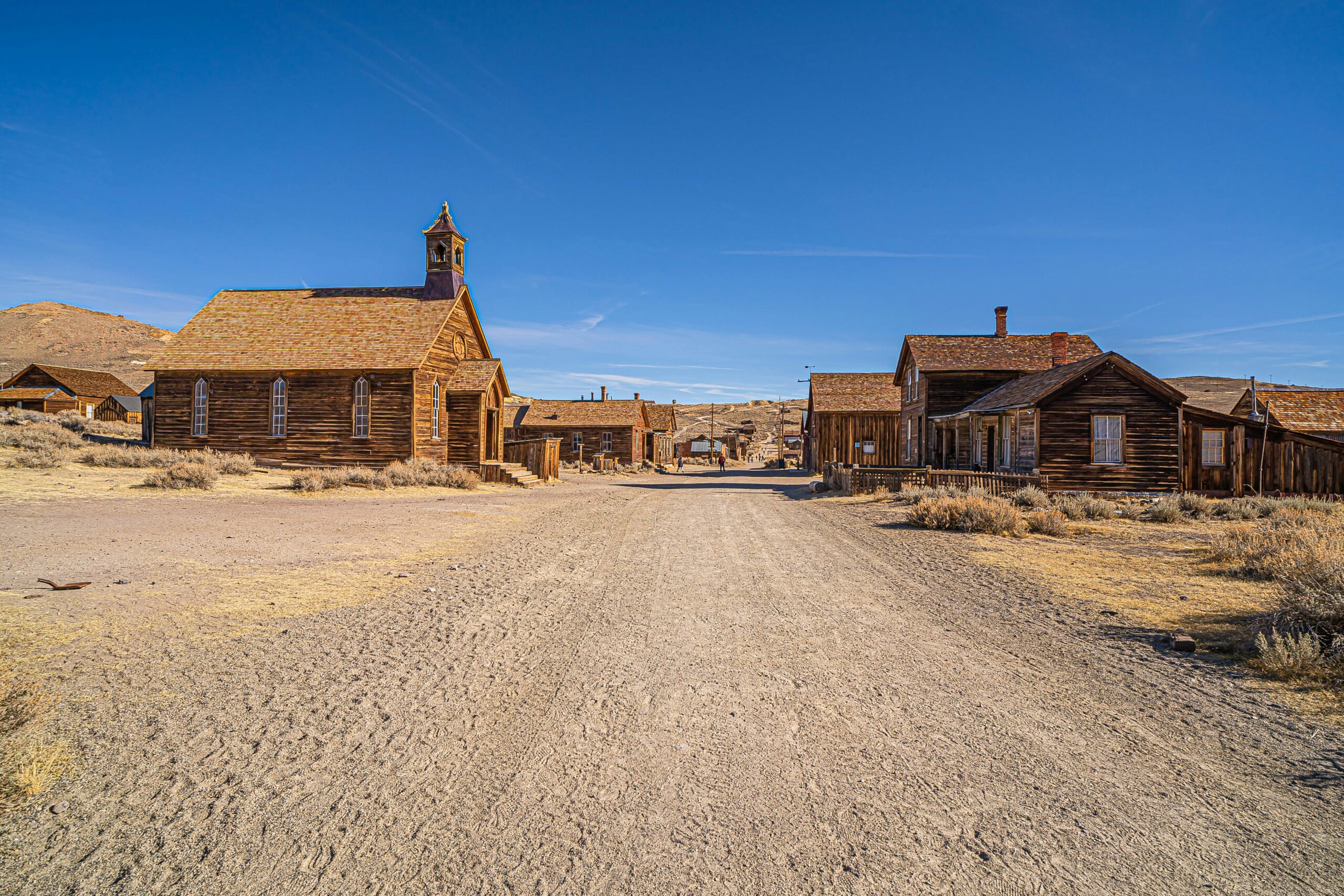 Wooden ghost town buildings lining a dirt road in Bodie, California.