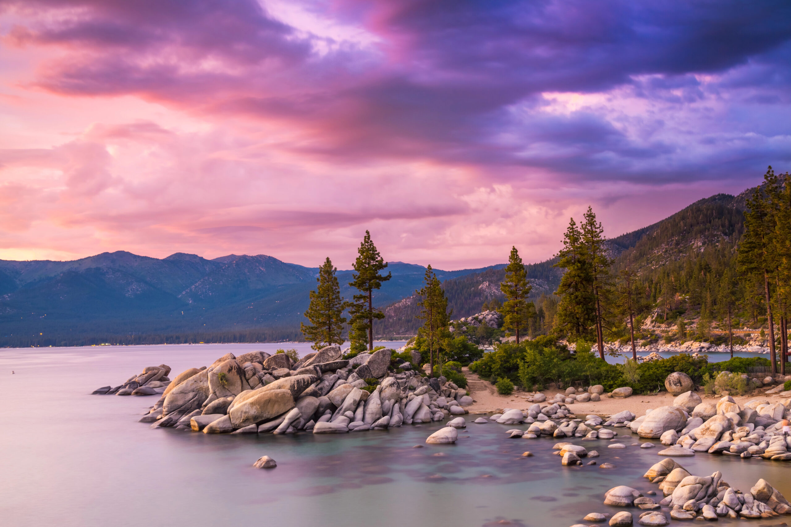 View of Lake Tahoe rocky coastline under a pink sunset.