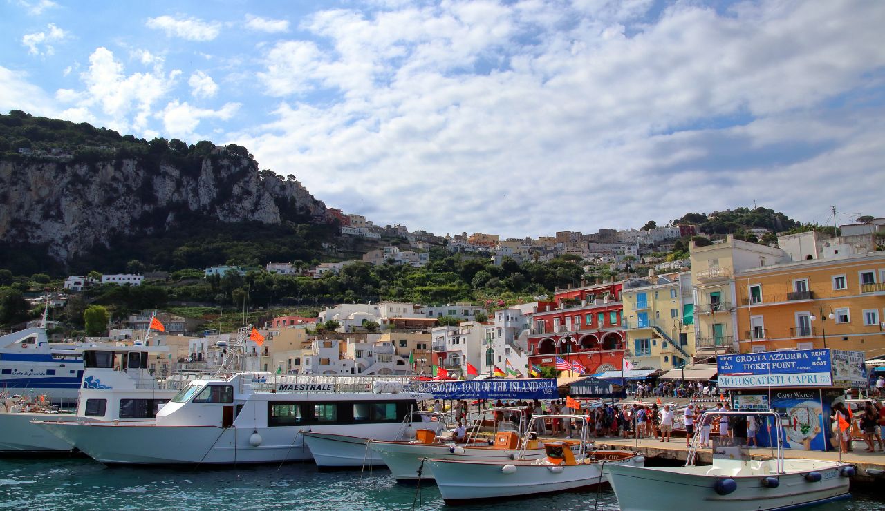 Busy marina with boats docked and colorful buildings on the island of Capri, Italy.
