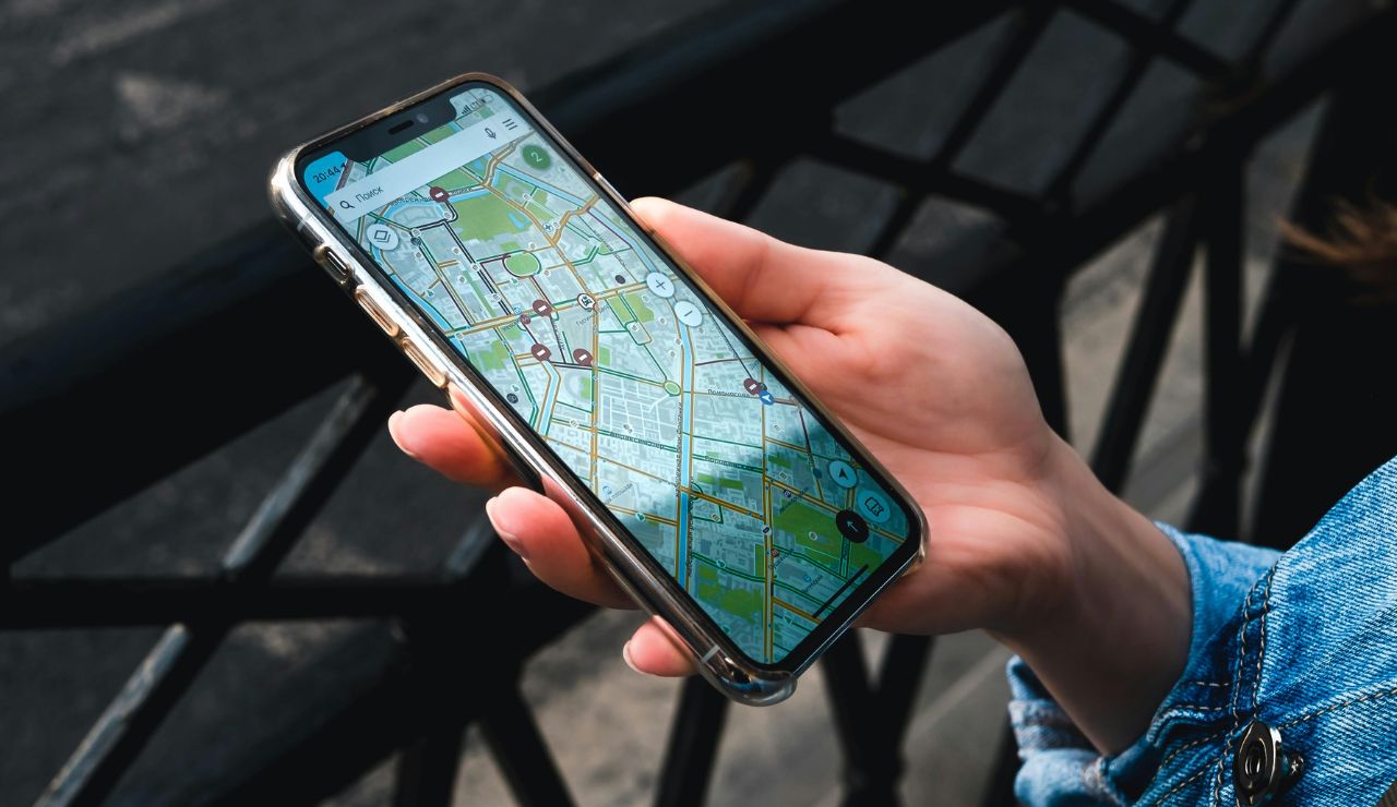 Traveler loading offline map on phone next to backpack, charger, and guidebook.