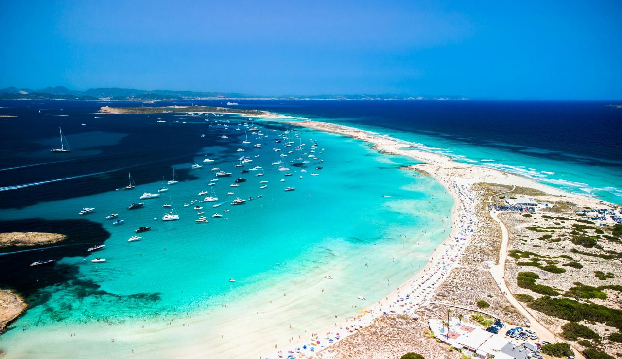 Aerial view of Formentera beach with turquoise waters and boats anchored offshore.
