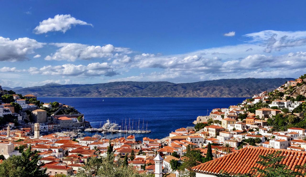 Scenic view of Hydra Island, Greece, with red-roofed buildings and blue sea.