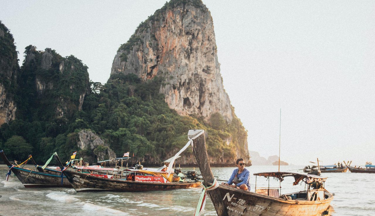 Longtail boats floating near limestone cliffs in Krabi