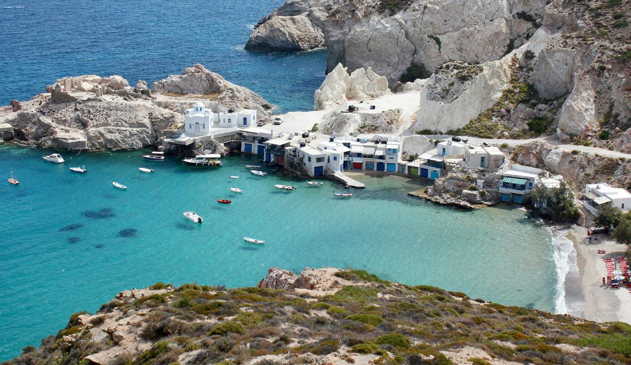 Small fishing village with whitewashed houses and boats in a turquoise bay.