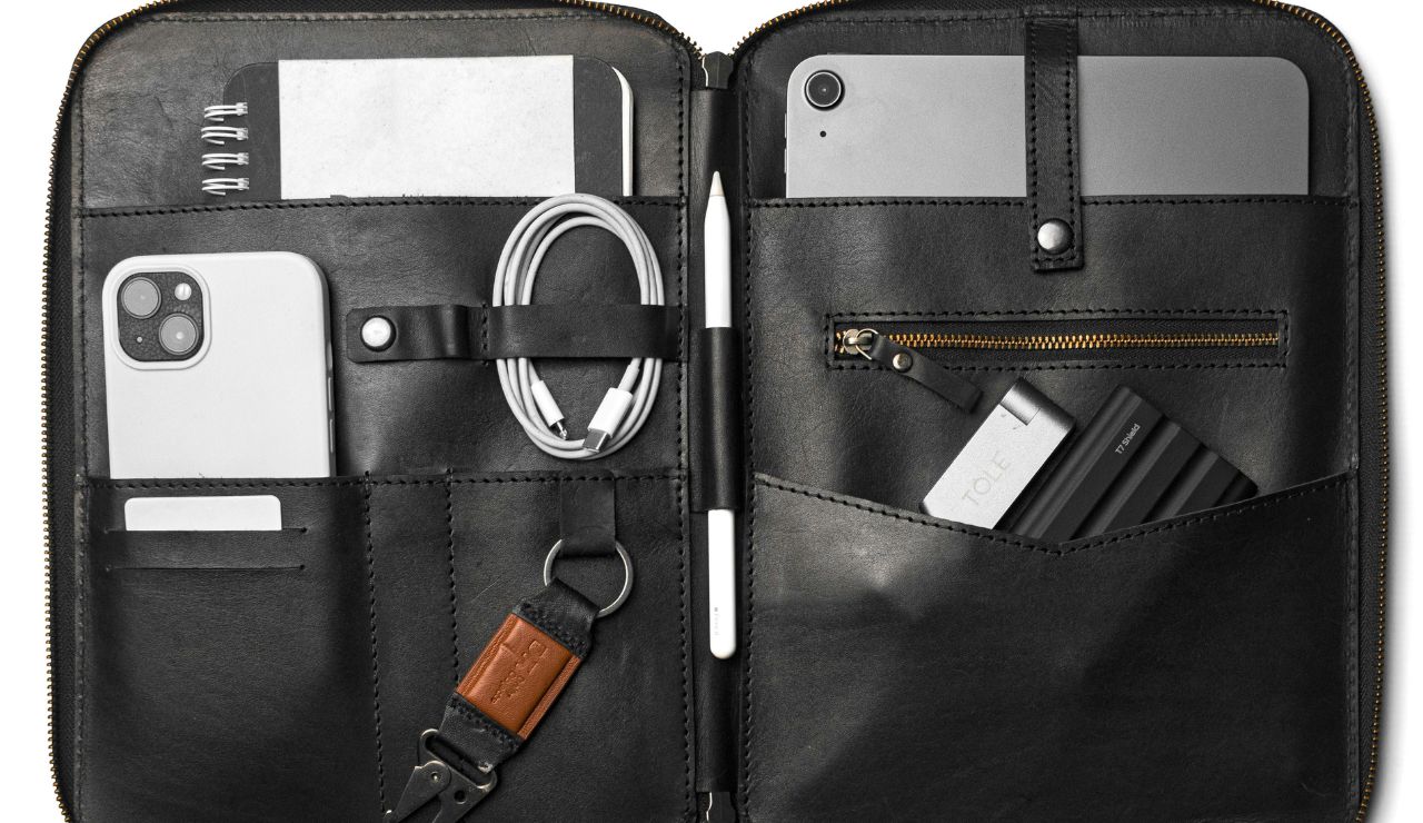 Open suitcase with universal adapter, chargers, medication, and toiletries.