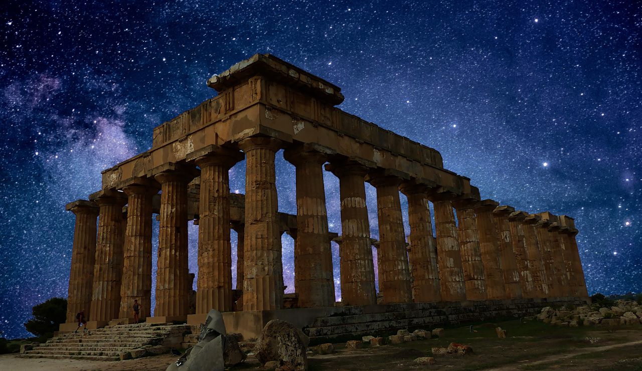Ancient Greek temple ruins under a starry night sky.