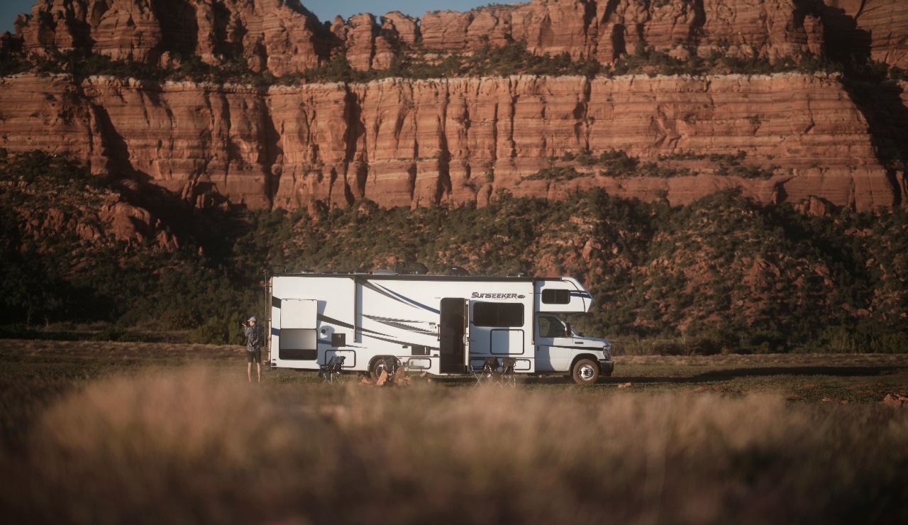 RV parked by Virgin River with Zion Canyon cliffs in the background.