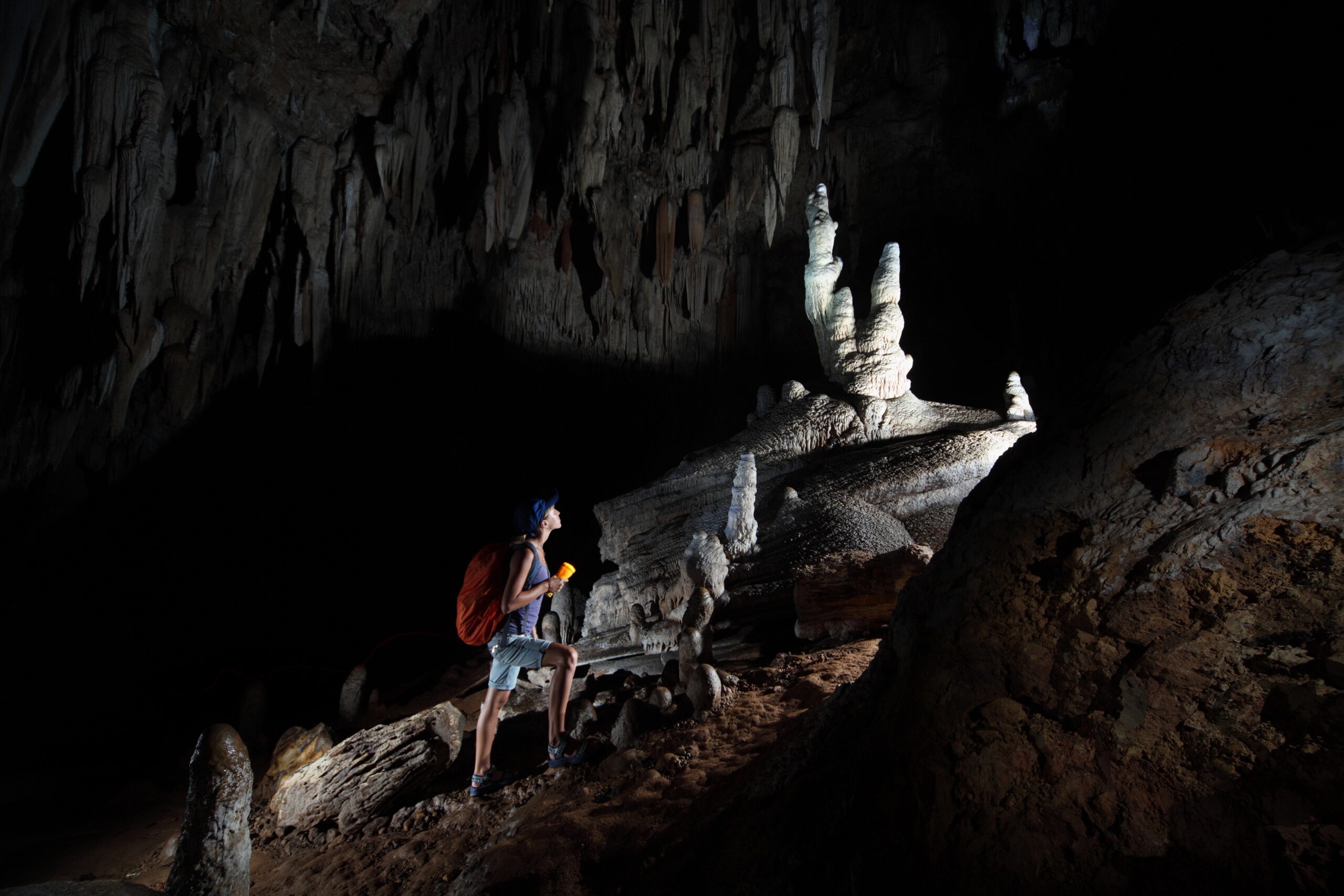 A backpacker with a flashlight exploring Cave of the Winds, one of the most romantic getaways in Colorado Spings.