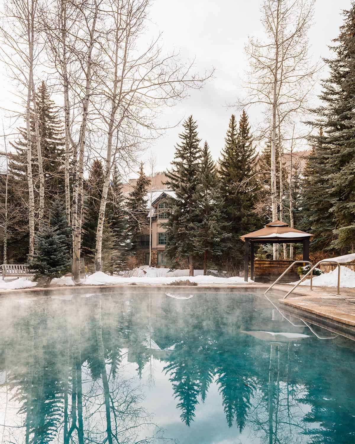 A steaming outdoor heated pool sits among snow and tall trees at Sonnenalp, one of the most romantic hotels in Vail.