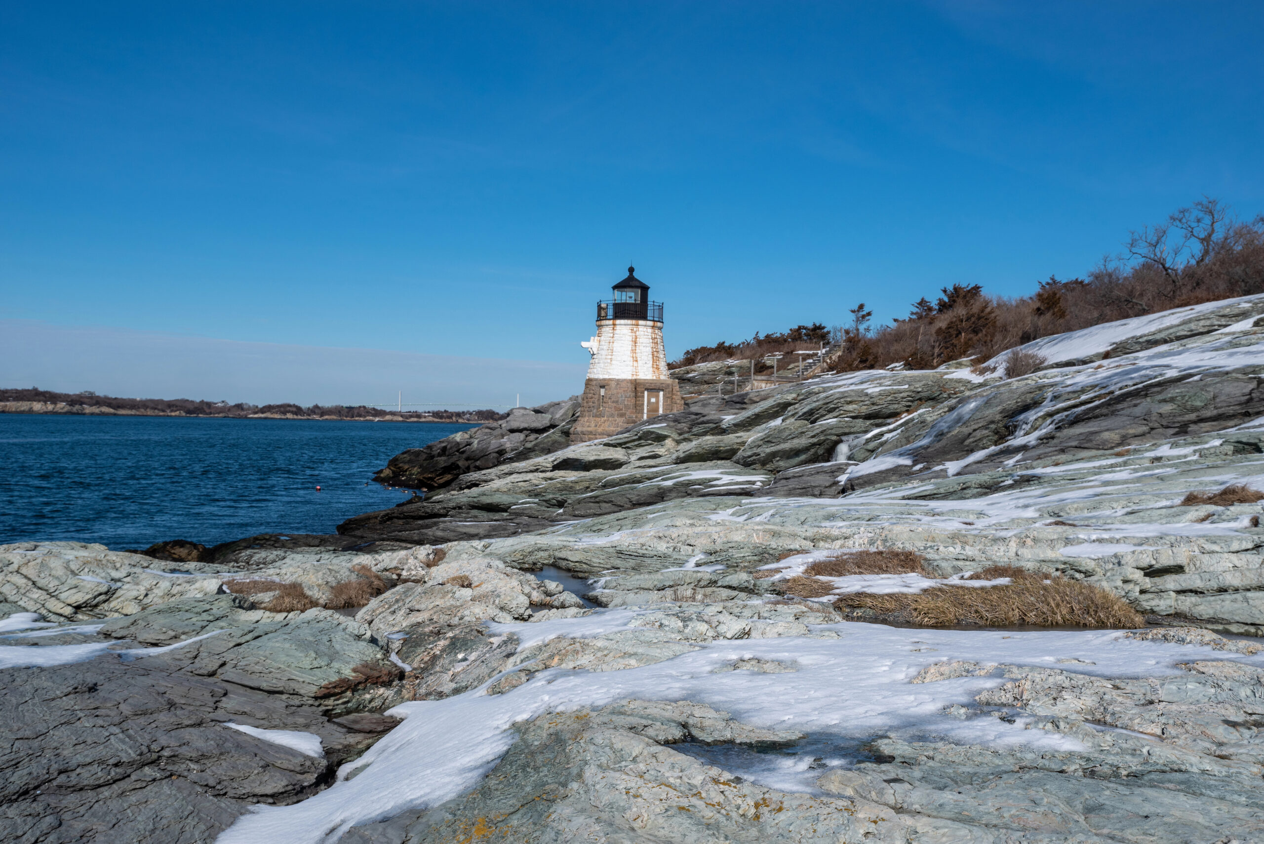 Lighthouse perched on a rocky coastline in Newport, Rhode Island, one of the most romantic winter getaways in the USA.