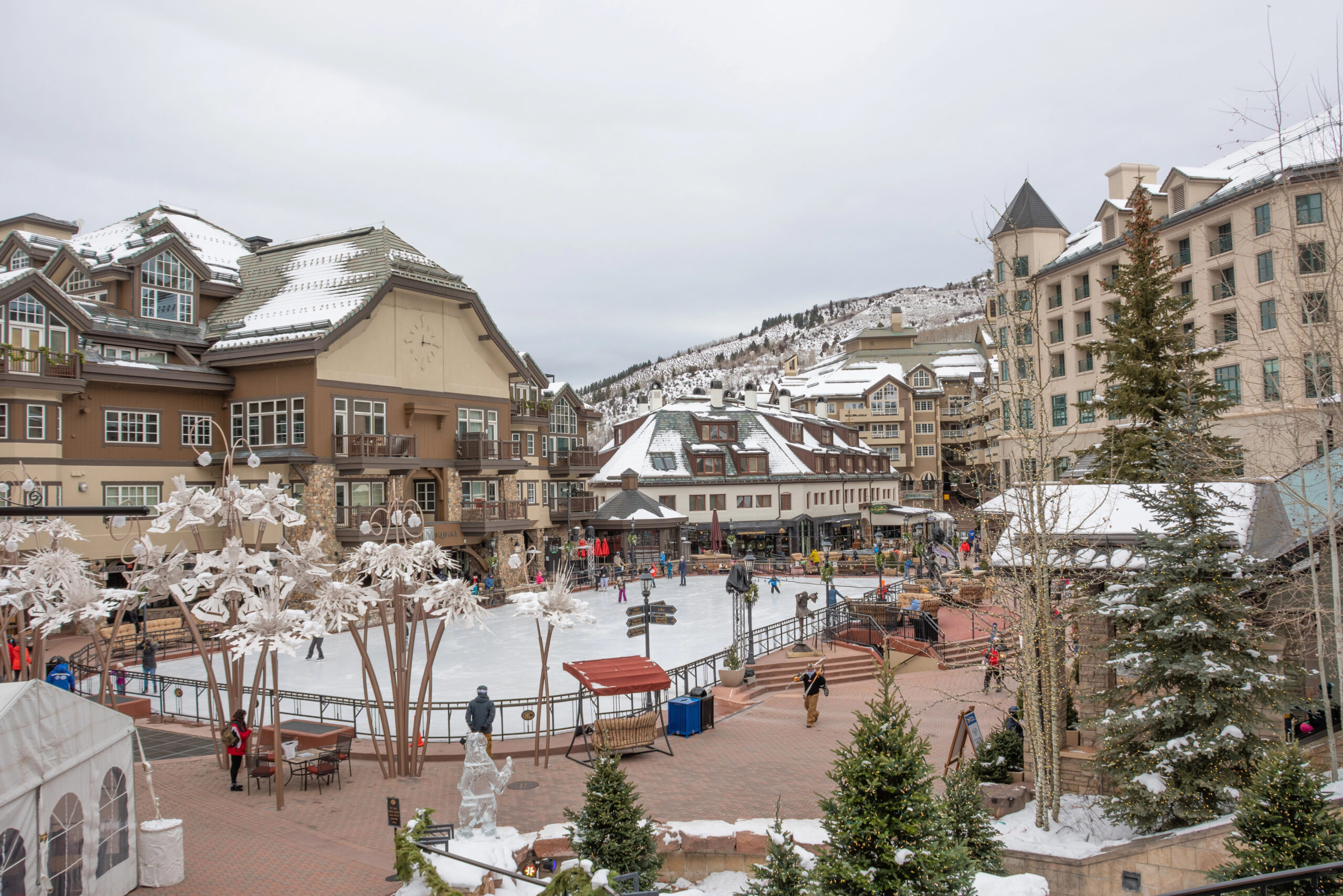 People ice skating at an outdoor rink bordered by alpine buildings in Beaver Creek. It's one of the most romantic things to do in Vail!