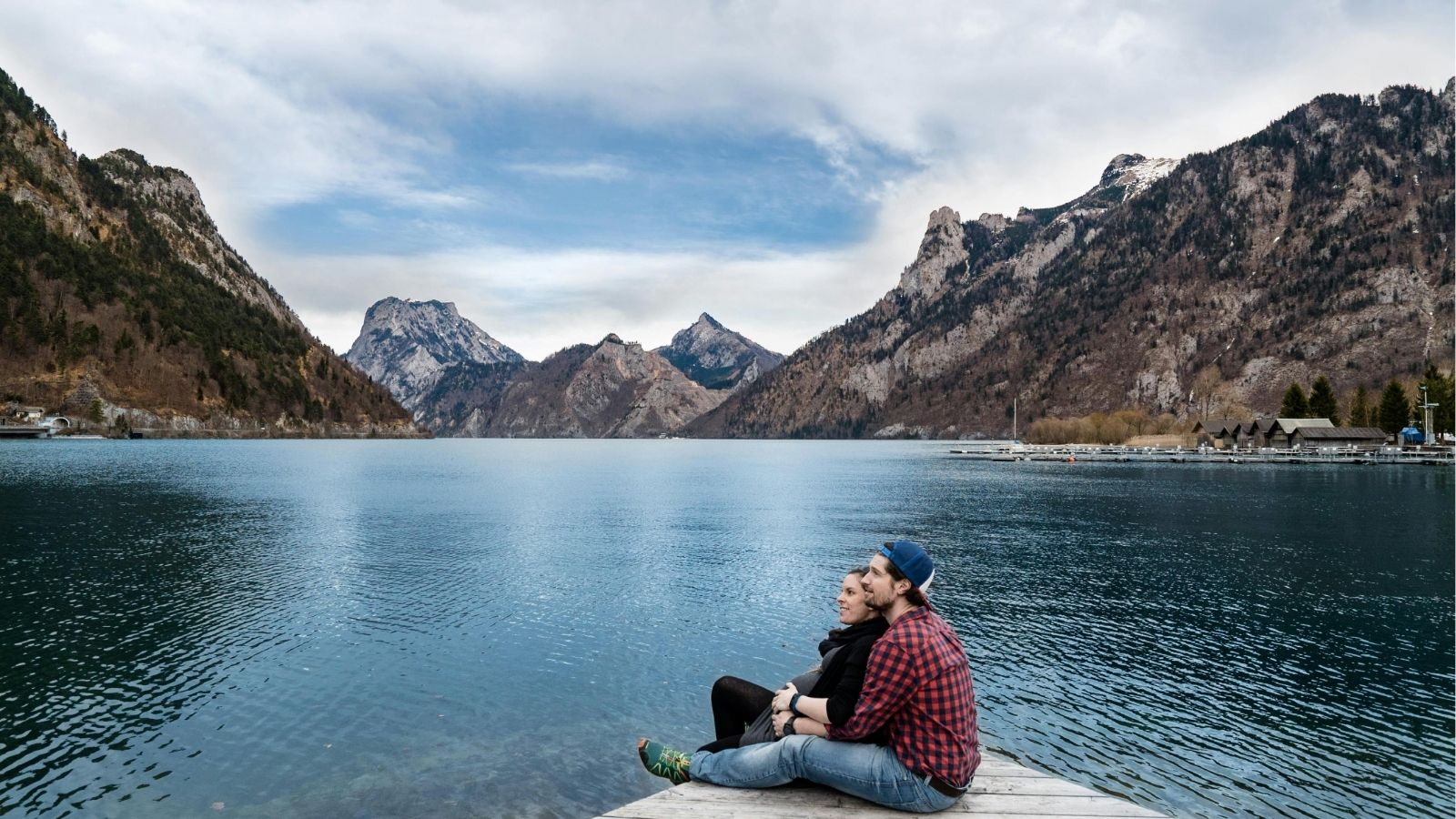 A photo of a couple cuddling by the lake.