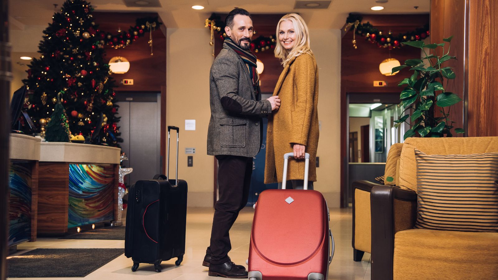 A middle aged couple at a holiday decorated hotel lobby.