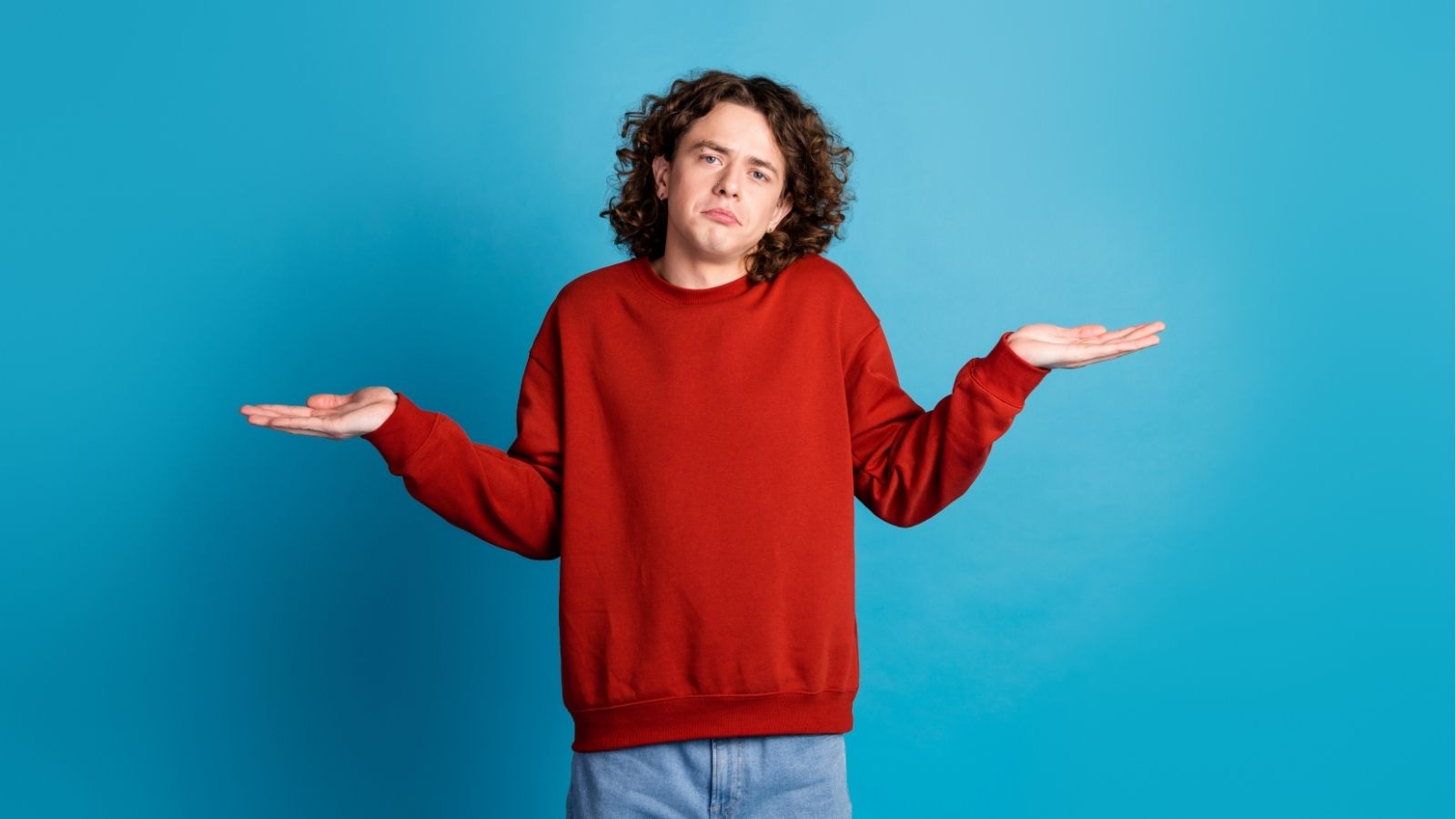 A man in a red sweater shrugging.