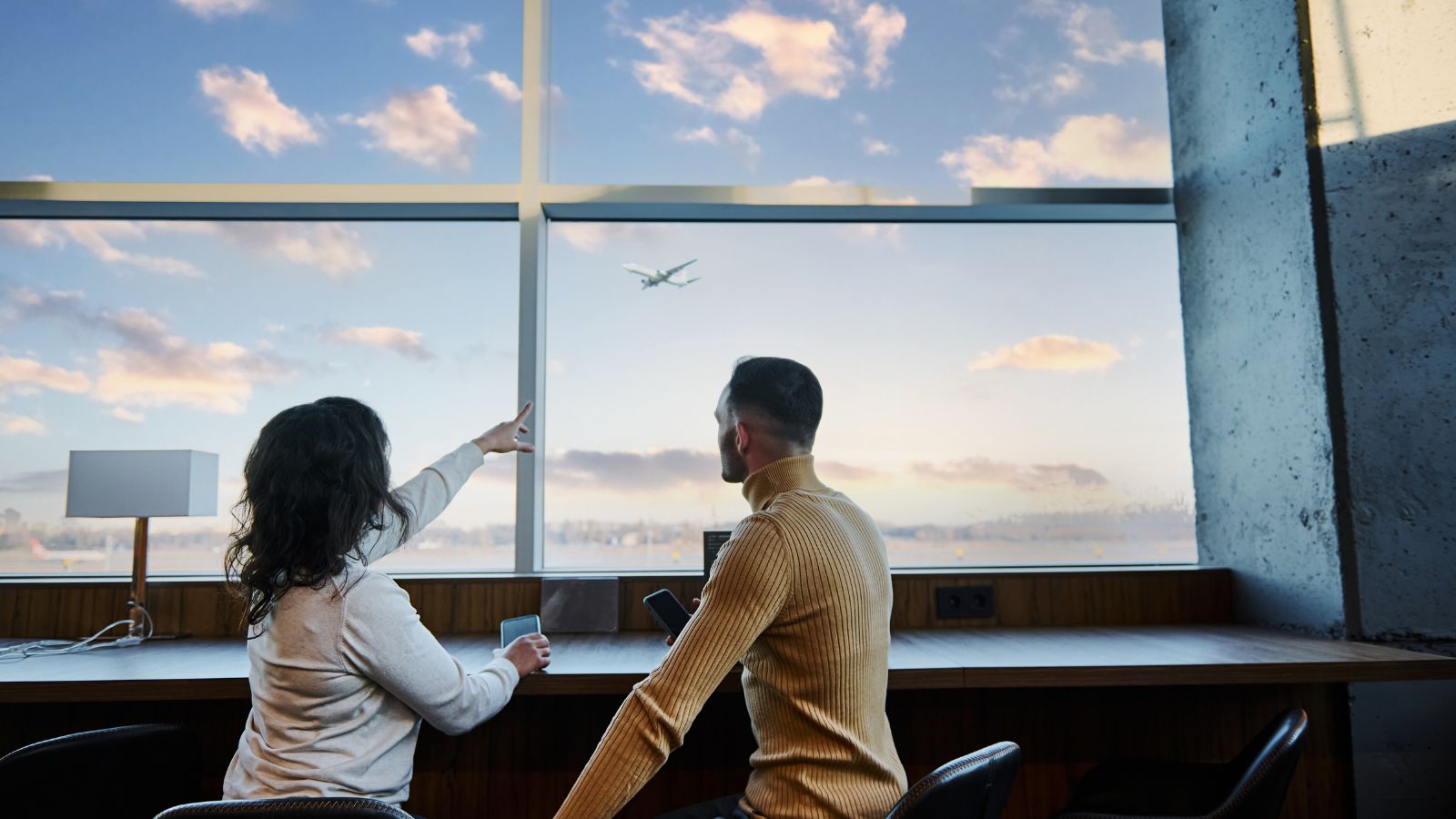 A couple sitting at an airport café or hotel lounge looking a phone.