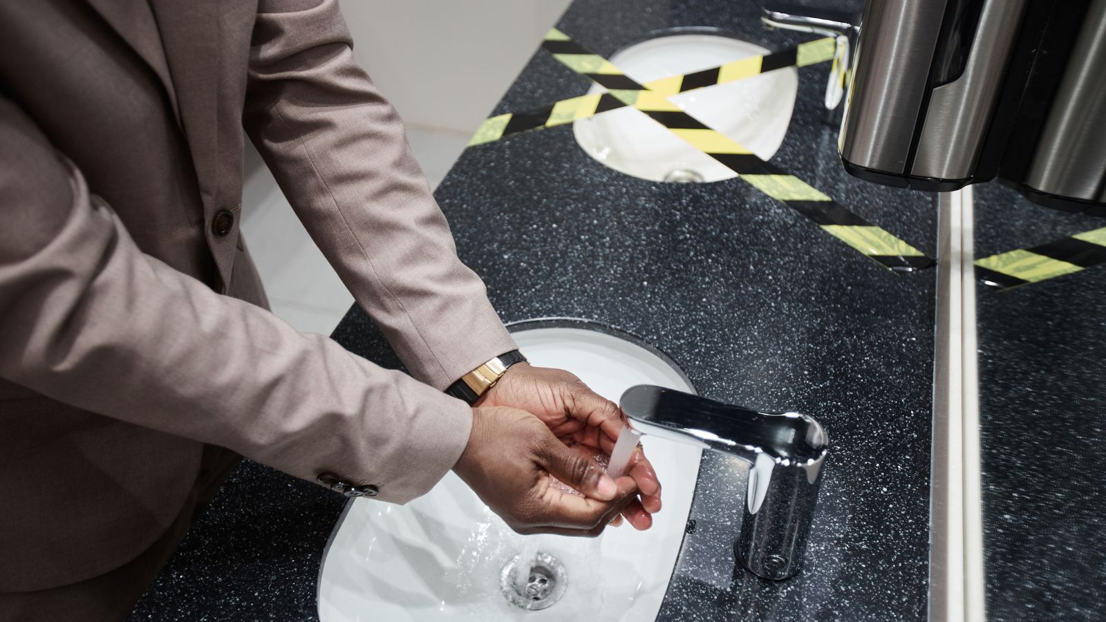A photo of Traveler using hand sanitizer or washing hands at airport restroom sink.