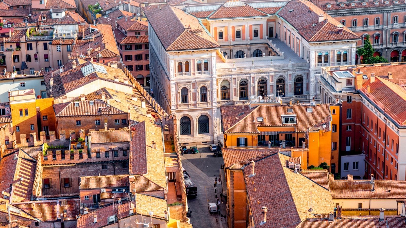 Aerial view of densely packed terracotta-roofed buildings and a central historic structure in an urban setting.