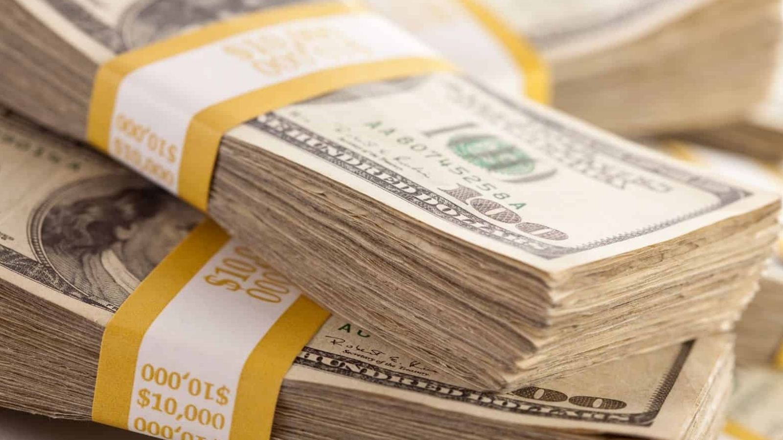 Stacks of $100 bills bundled with yellow bands marked "$10,000".