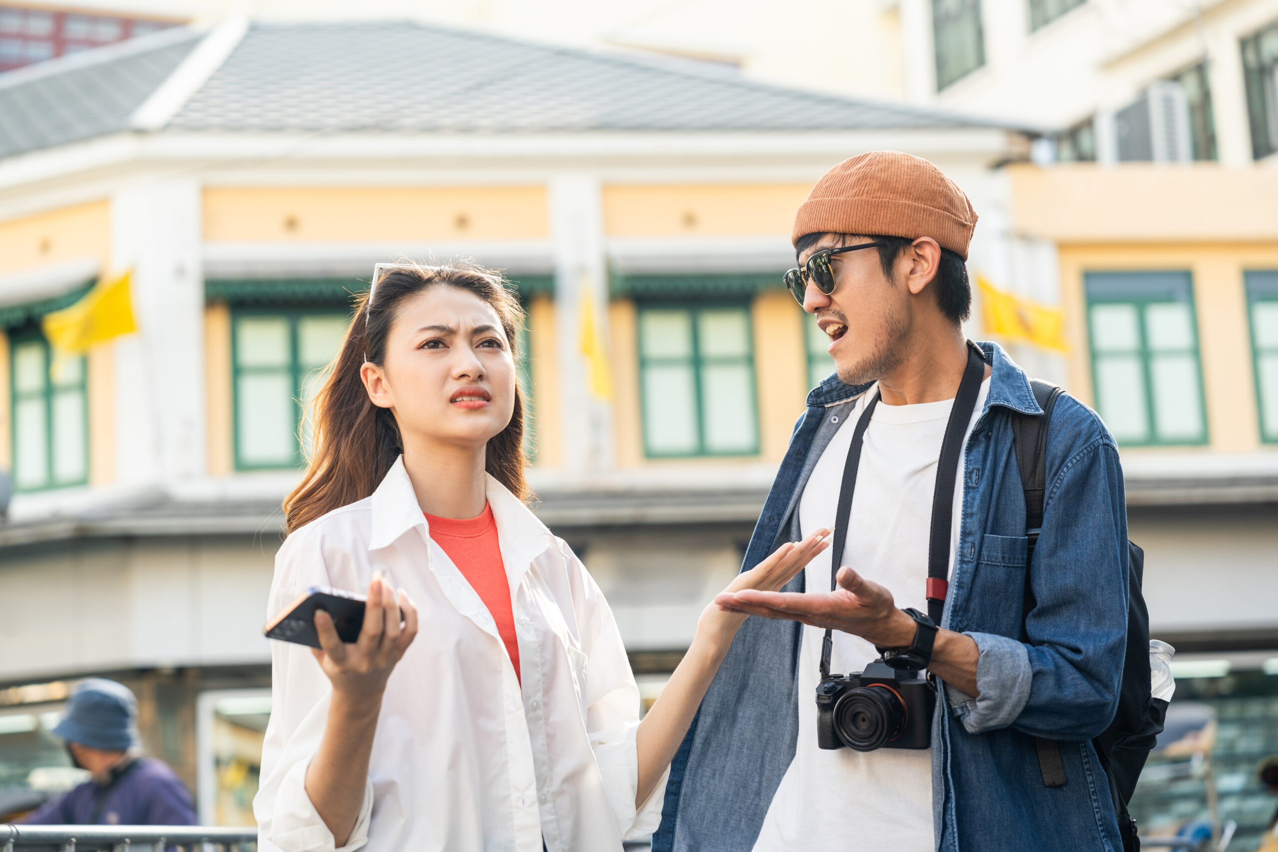 A young Asian couple man and woman traveling backpacker in Khaosan Road outdoor market in Bangkok Thailand. Happy couple tourist walking in the downtown street traditional market.