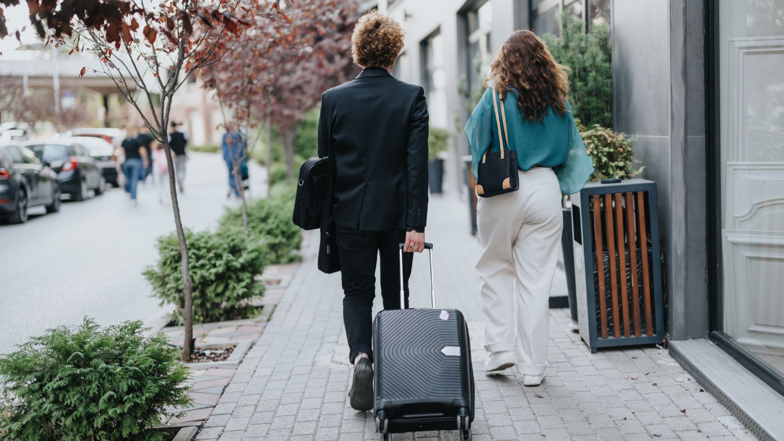 A photo of Couple arriving in a new city pulling a small suitcase.