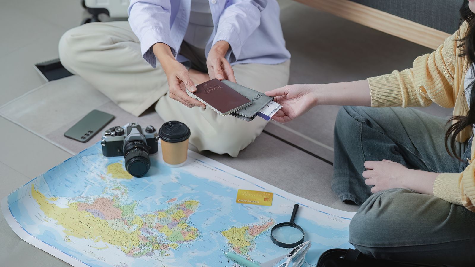 A picture of two hands with a passport and a map in front of them.
