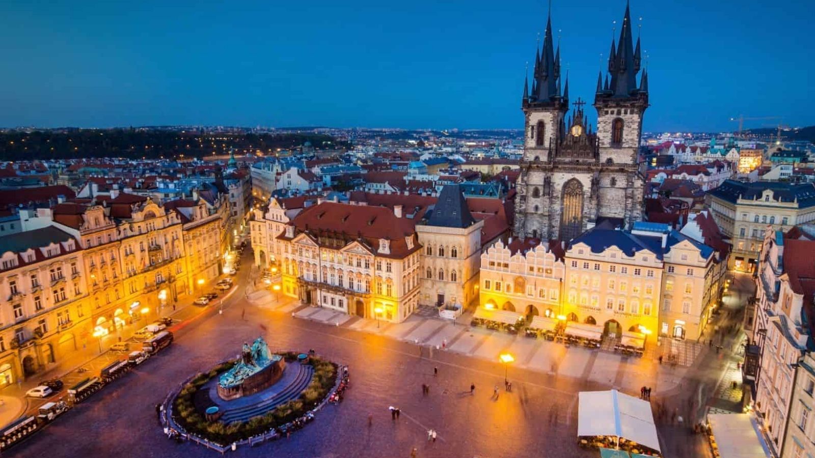 Aerial dusk view of Prague's Old Town Square with the lit Church of Our Lady before Týn and Jan Hus Monument.