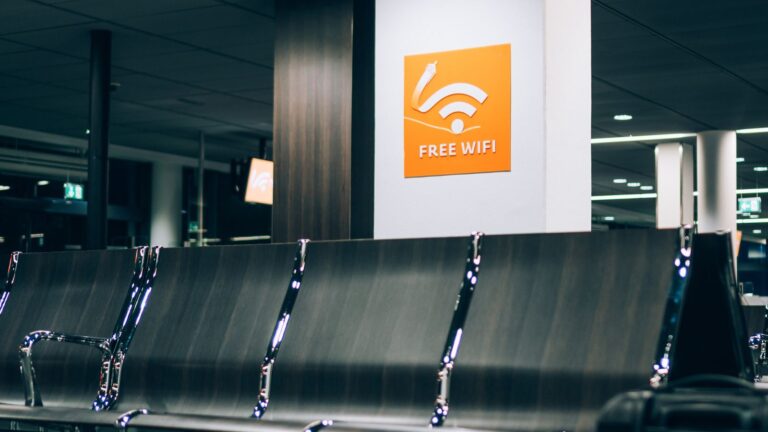Empty airport seating with a "Free WiFi" sign above on a white wall.