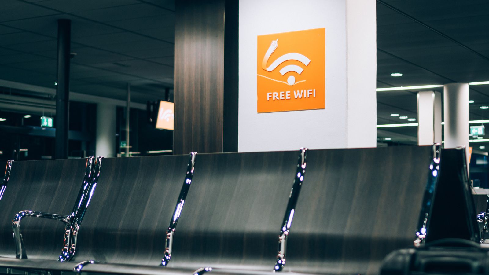 Empty airport seating with a "Free WiFi" sign above on a white wall.