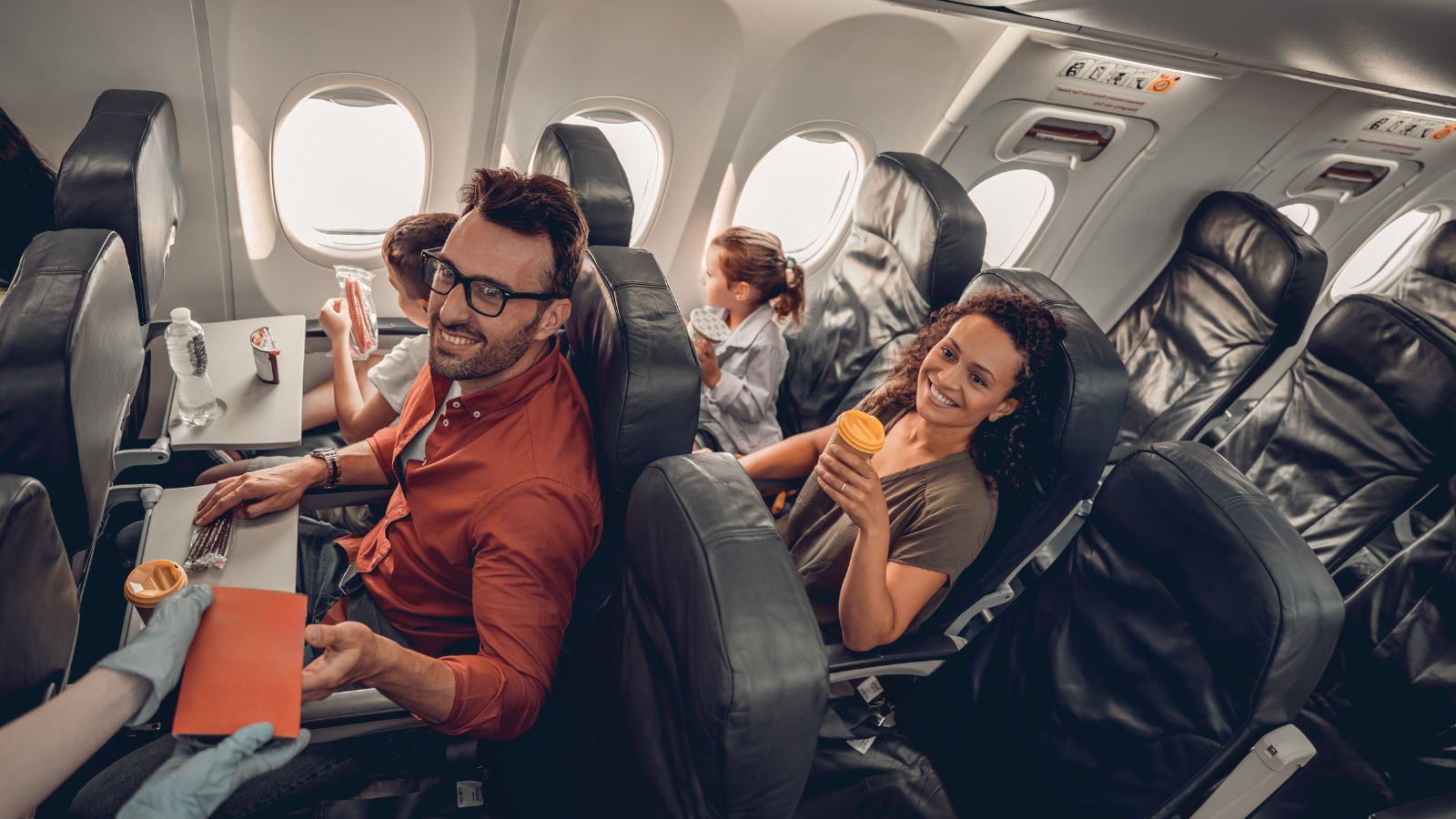A photo of group of people seated in a plane happily.