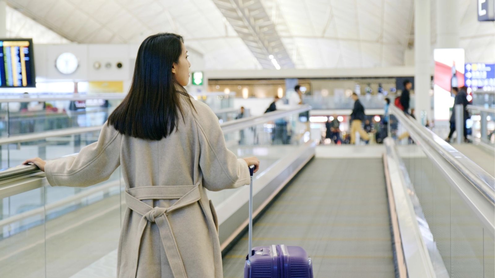 A picture of a girl's back walking with a luggage.