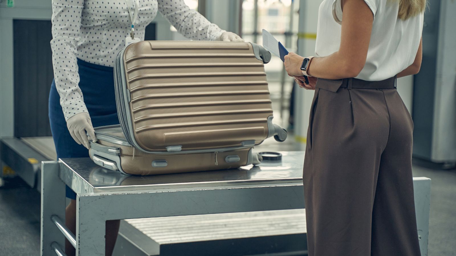 A photo of Airport security or customs inspection scene where a traveler’s luggage is open.