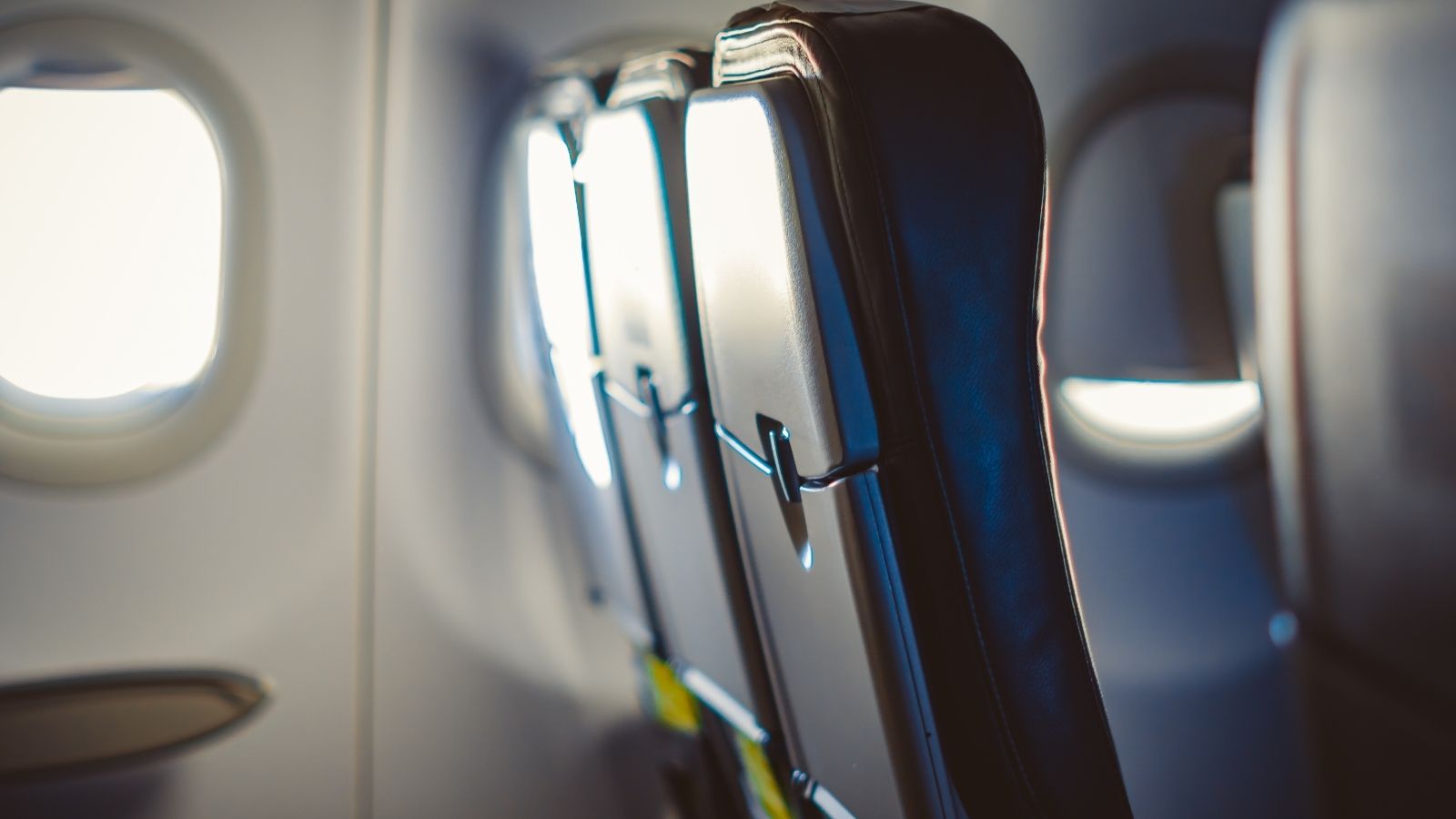 Two empty airplane seats by a sunlit window.